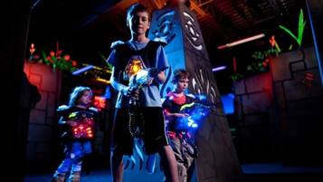 A child in a costume holding a glowing object, standing in front of a large, illuminated structure with a dragon design.