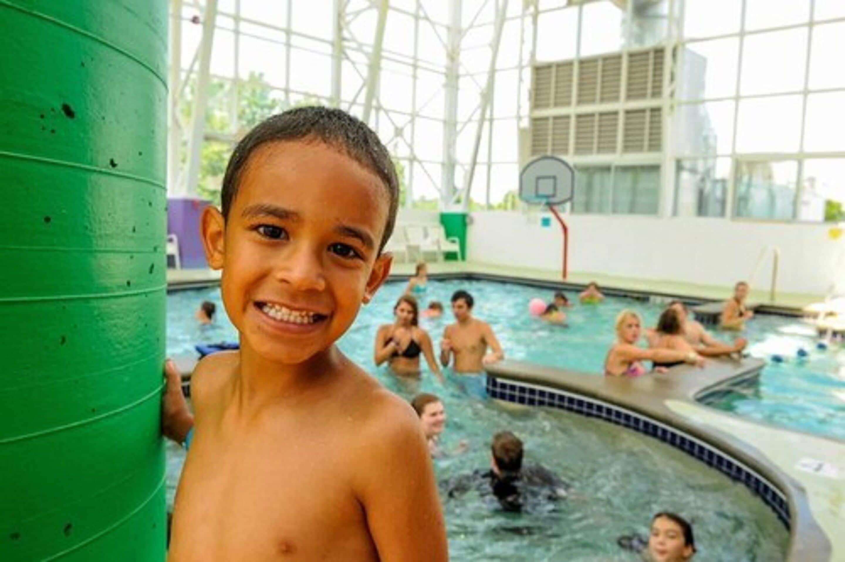 A swimming pool area with a basketball hoop in the background.