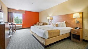 Een hotelkamer met een groot bed, nachtlampjes, een bureau en uitzicht op groen.