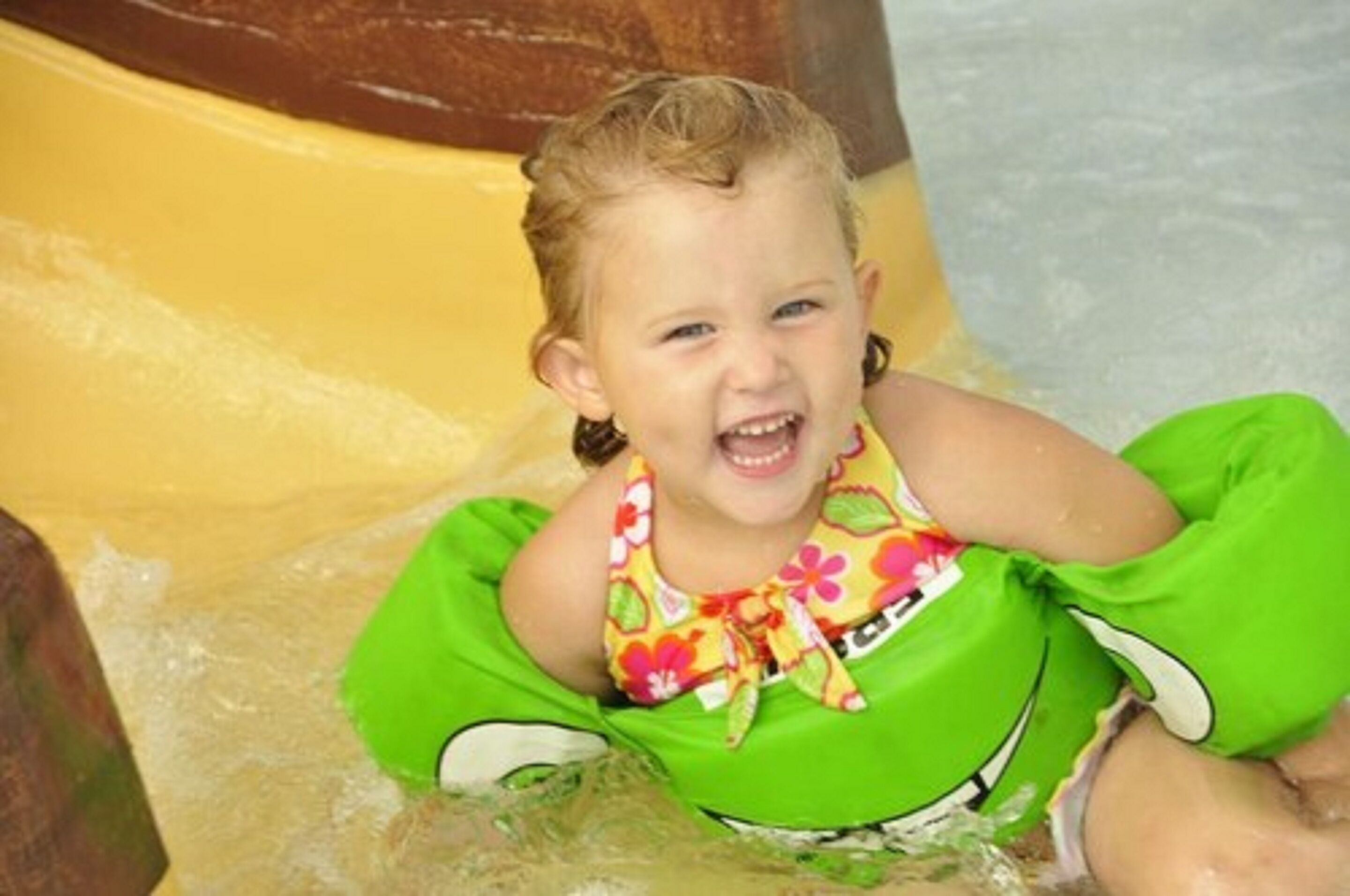 A child in a pool with a green inflatable float.