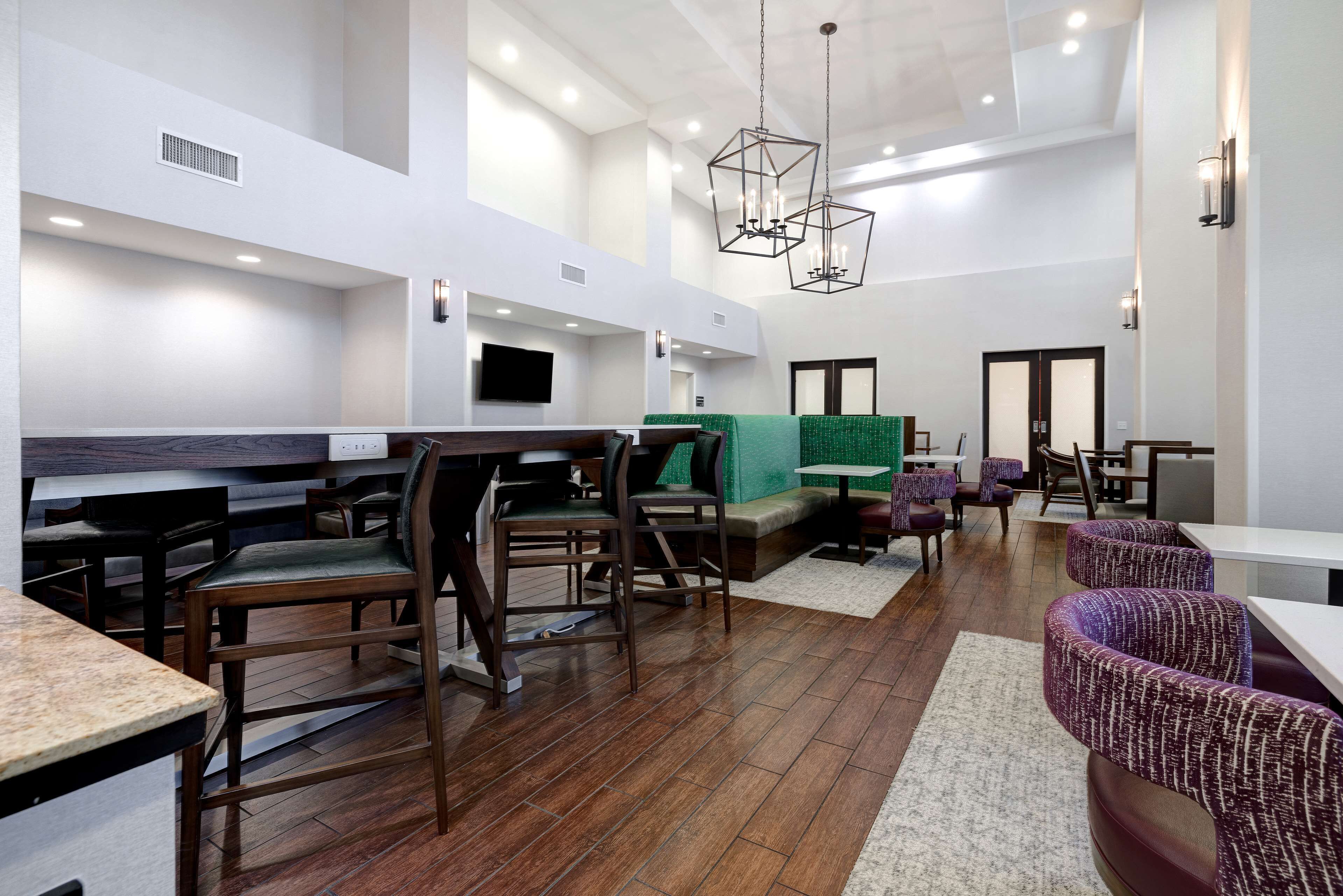 A modern interior with wooden flooring, seating areas, and a flat-screen TV mounted on the wall.