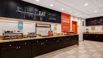 A breakfast bar with a sign reading "Happy Breakfast Starts Here!" and a sign for the bakery.
