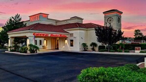 Un hotel con tejado de tejas rojas, una torre de reloj y un letrero que indica Gateway Studios Suites.