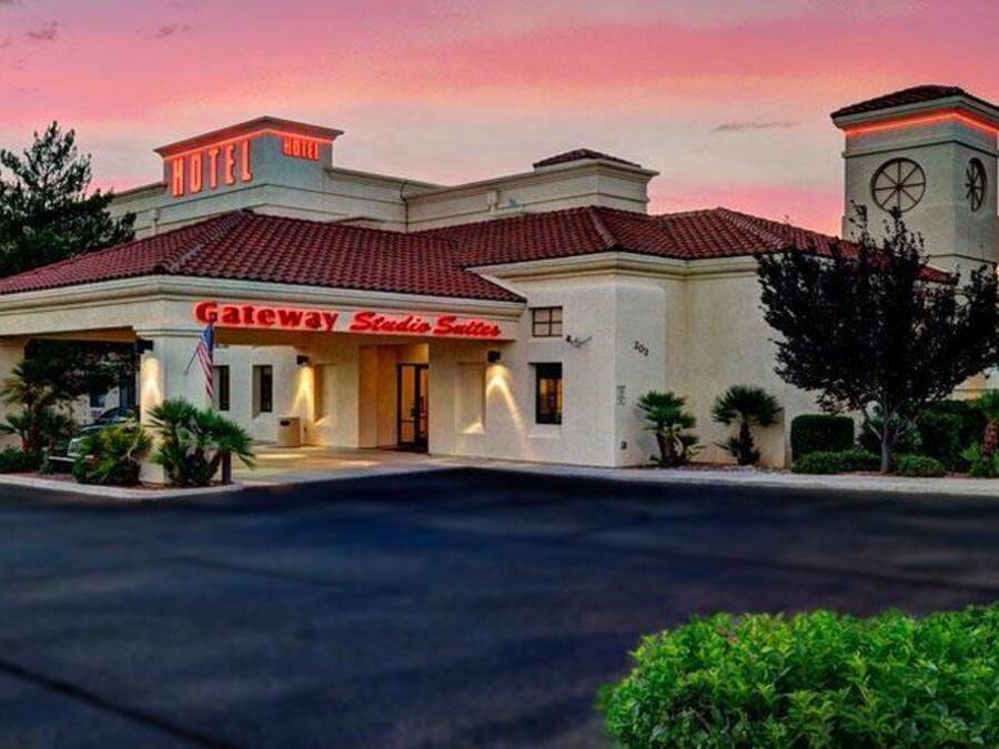 A hotel with a red-tiled roof, a clock tower, and a sign for Gateway Studios Suites.