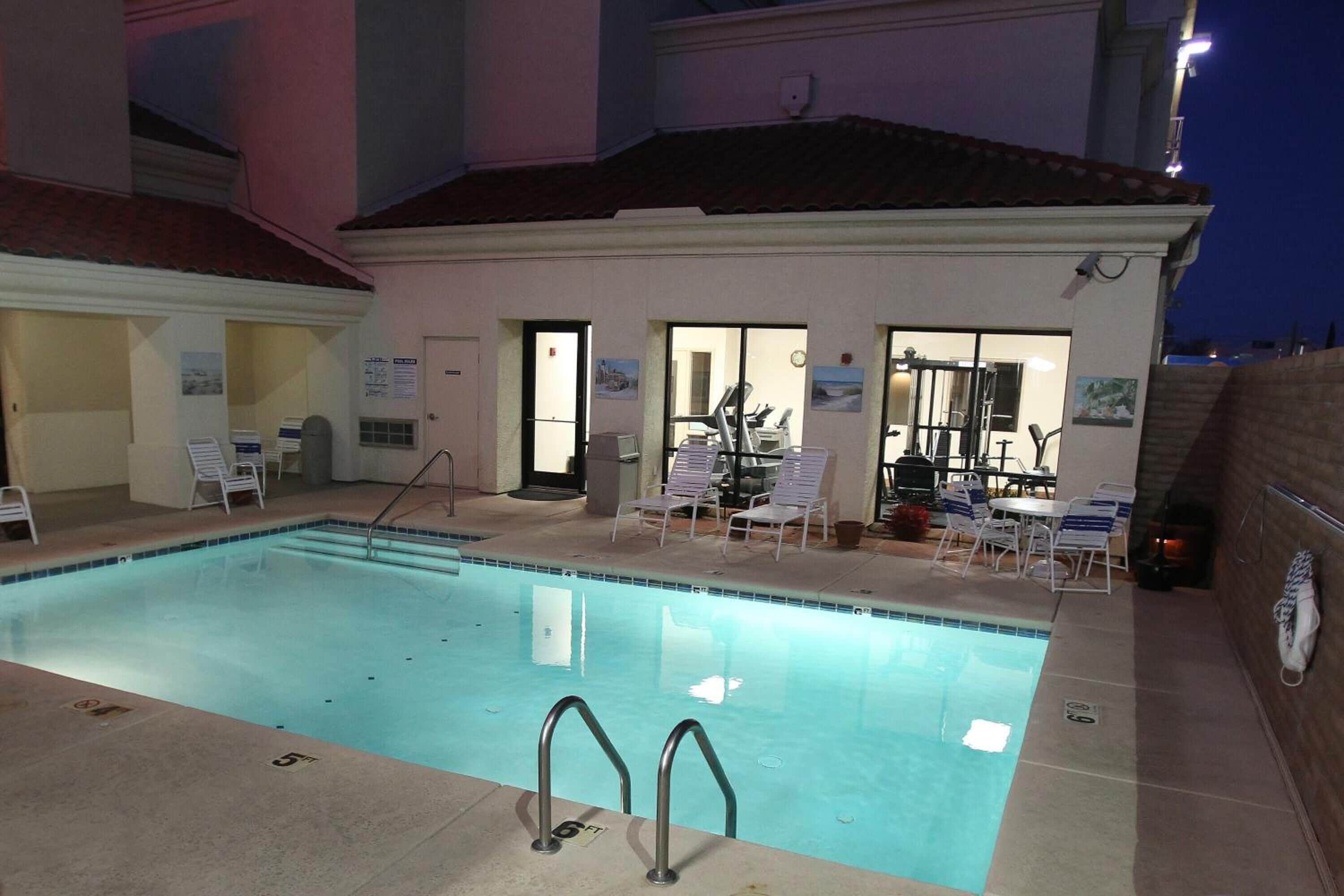 Piscina con sillones de descanso y un área cubierta con mesas y sillas.
