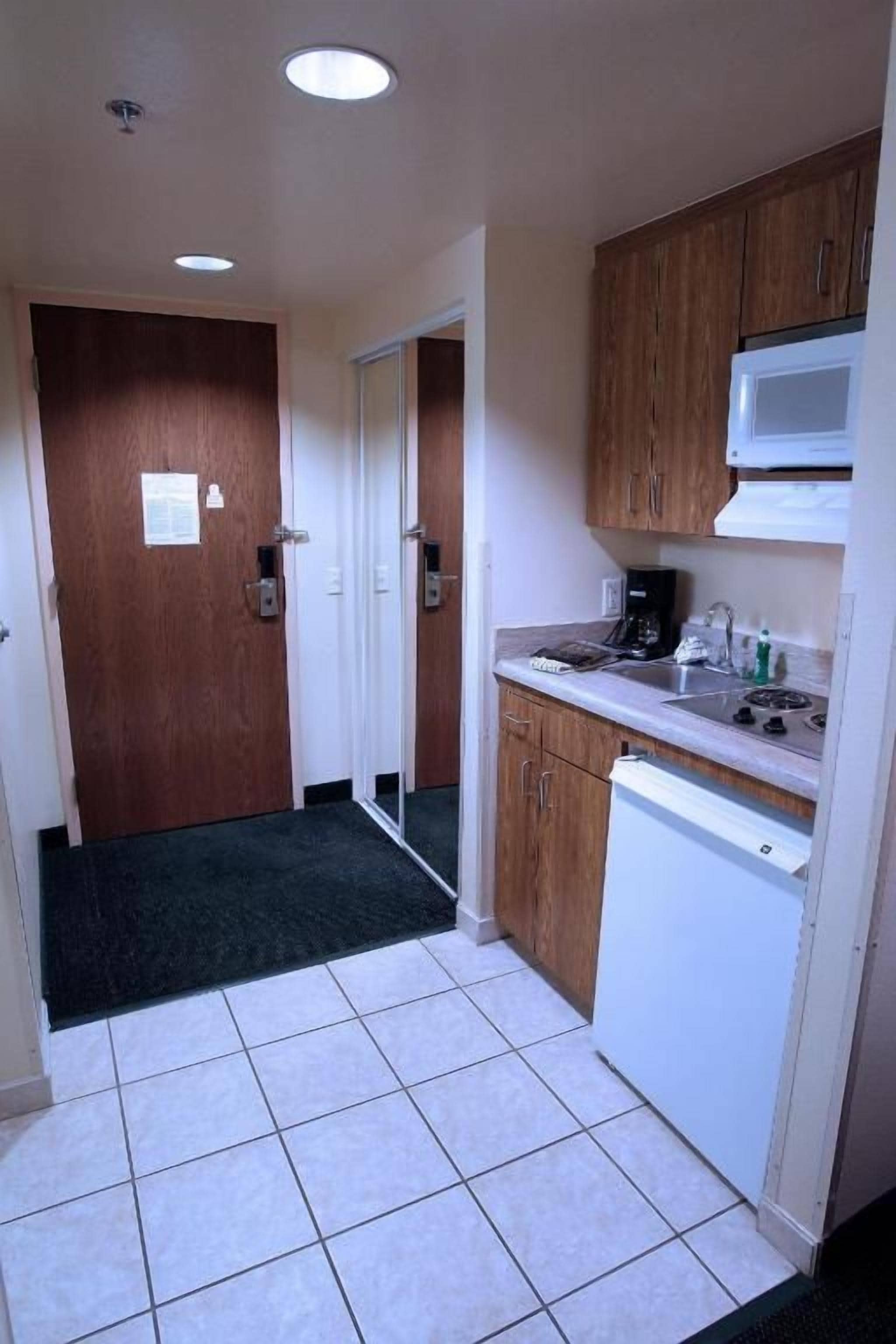 A compact kitchen with wooden cabinets, a white microwave, and a dishwasher.