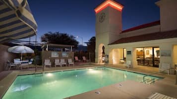 Una piscina al aire libre, sombrillas, sillones reclinables de piscina