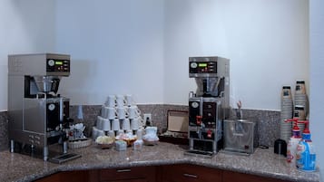 Una estación de café con dos máquinas de espresso, una pila de vasos desechables y diversos accesorios para preparar café.
