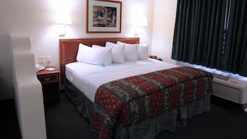 Une chambre d’hôtel avec un grand lit, deux lampes de chevet, un tableau au mur, une fenêtre avec des rideaux et un radiateur.