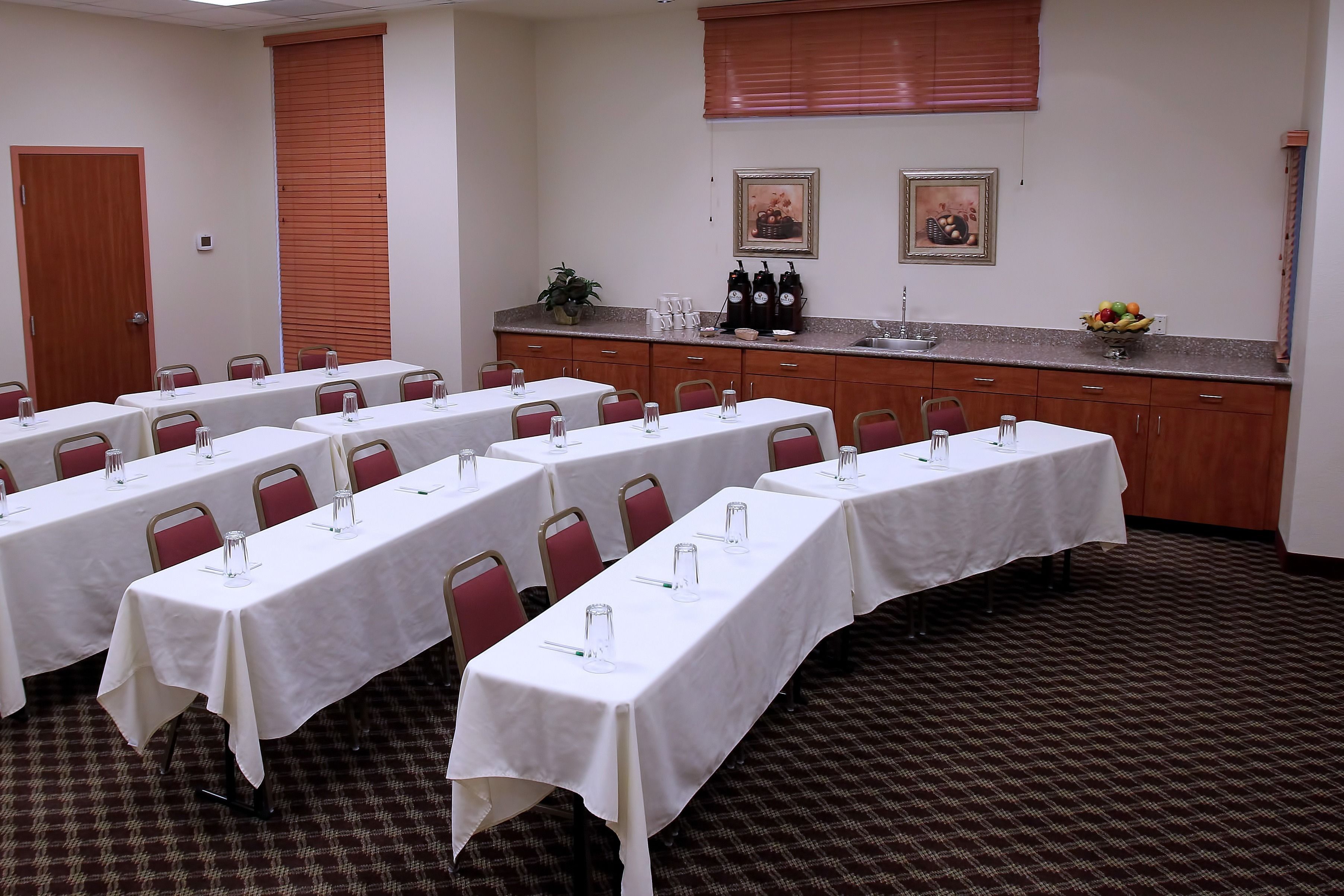 A conference room with long tables, chairs, a buffet counter, and a patterned carpet.