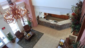 Un vestíbulo con mostrador de recepción, zona de estar y un candelabro decorativo.