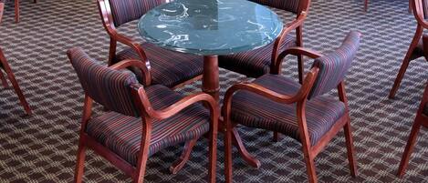 A conference room with round tables and chairs, a kitchen area, and three framed paintings on the wall.
