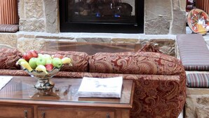 Una chimenea de piedra con televisión, un frutero y un sofá estampado.