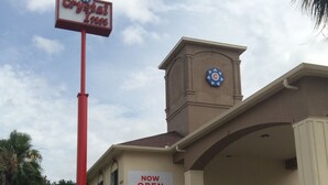 A building with a sign reading 'Crystal Inn' and a 'NOW OPEN' sign.
