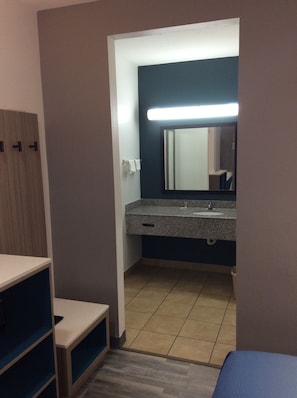 Un baño con lavamanos, espejo y toallero.