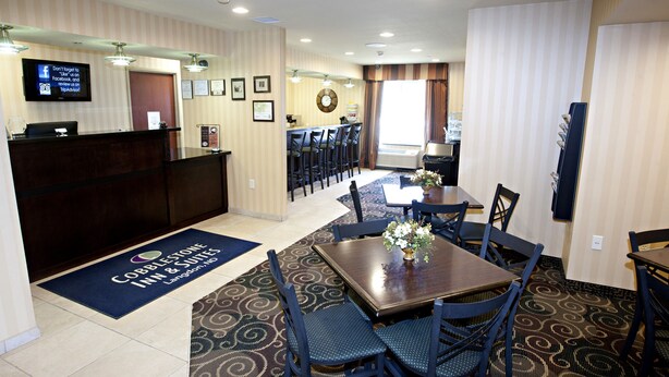 Un vestíbulo de hotel con una recepción, un comedor con mesas y sillas, y un reloj en la pared.