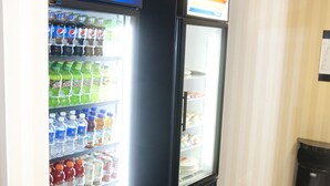 Zona de máquinas expendedoras con un refrigerador de Pepsi y una nevera, ambos llenos de bebidas.