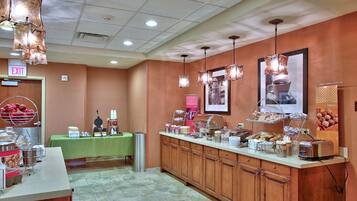 A buffet area with a green table, various food items, and a trash can.