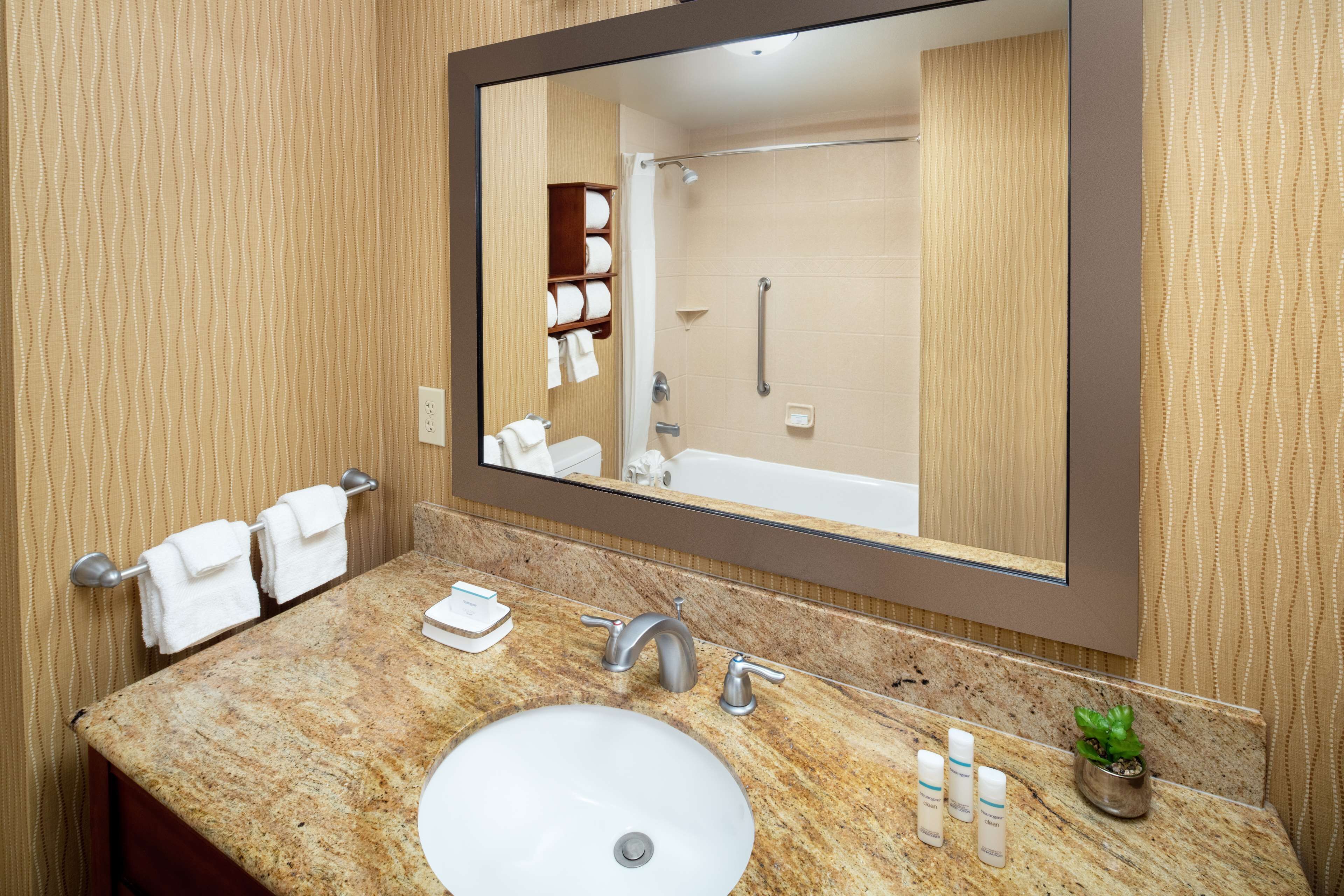 A bathroom with a marble sink, a large mirror, a towel rack, and a shower area.