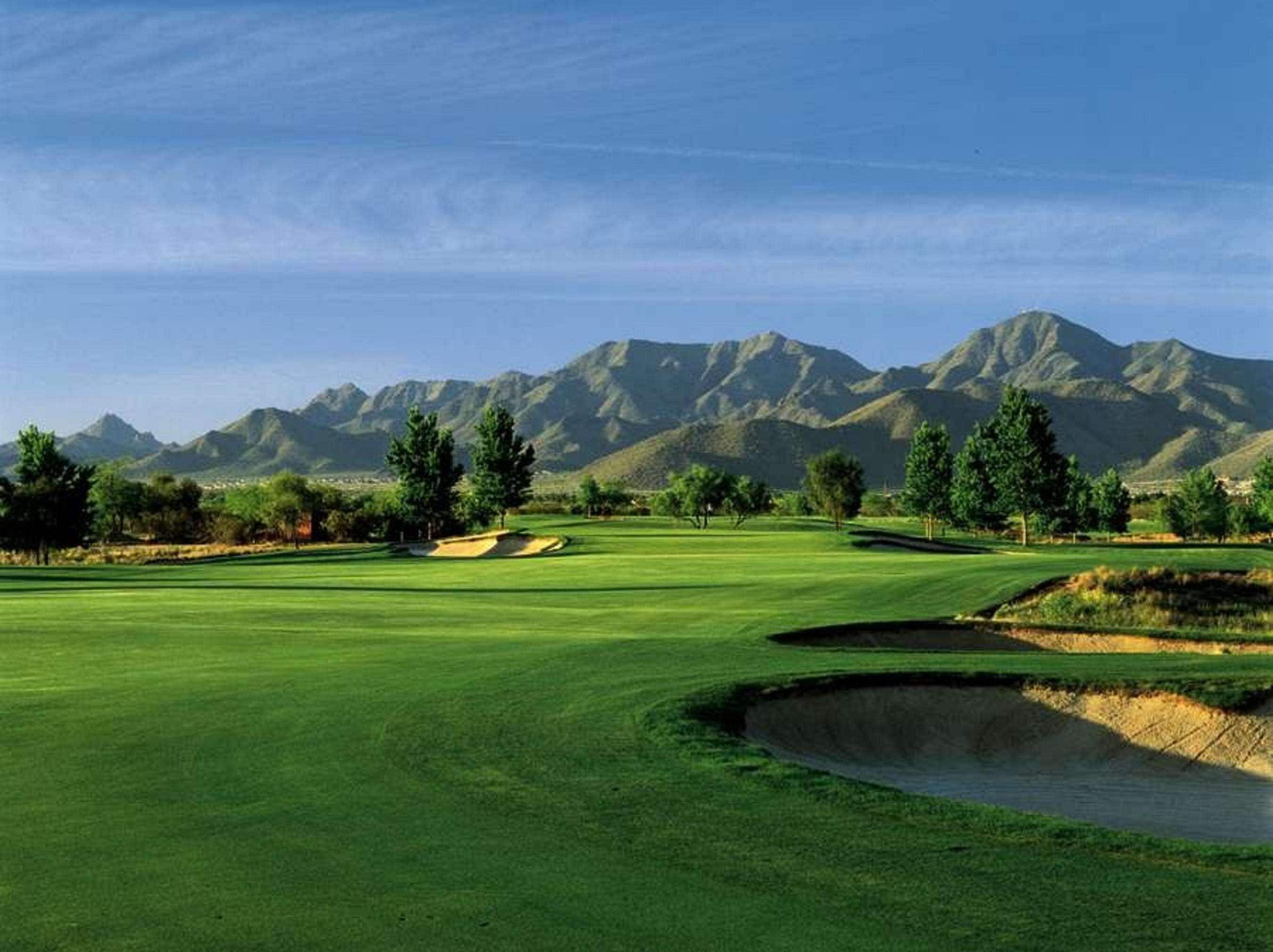 Campo de golf con una vista despejada de montañas al fondo.