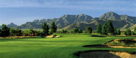 Campo de golf con una vista despejada de montañas al fondo.