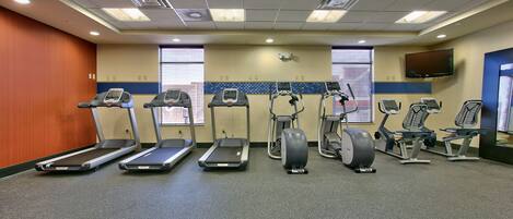 A fitness room with treadmills, elliptical machines, and stationary bikes.