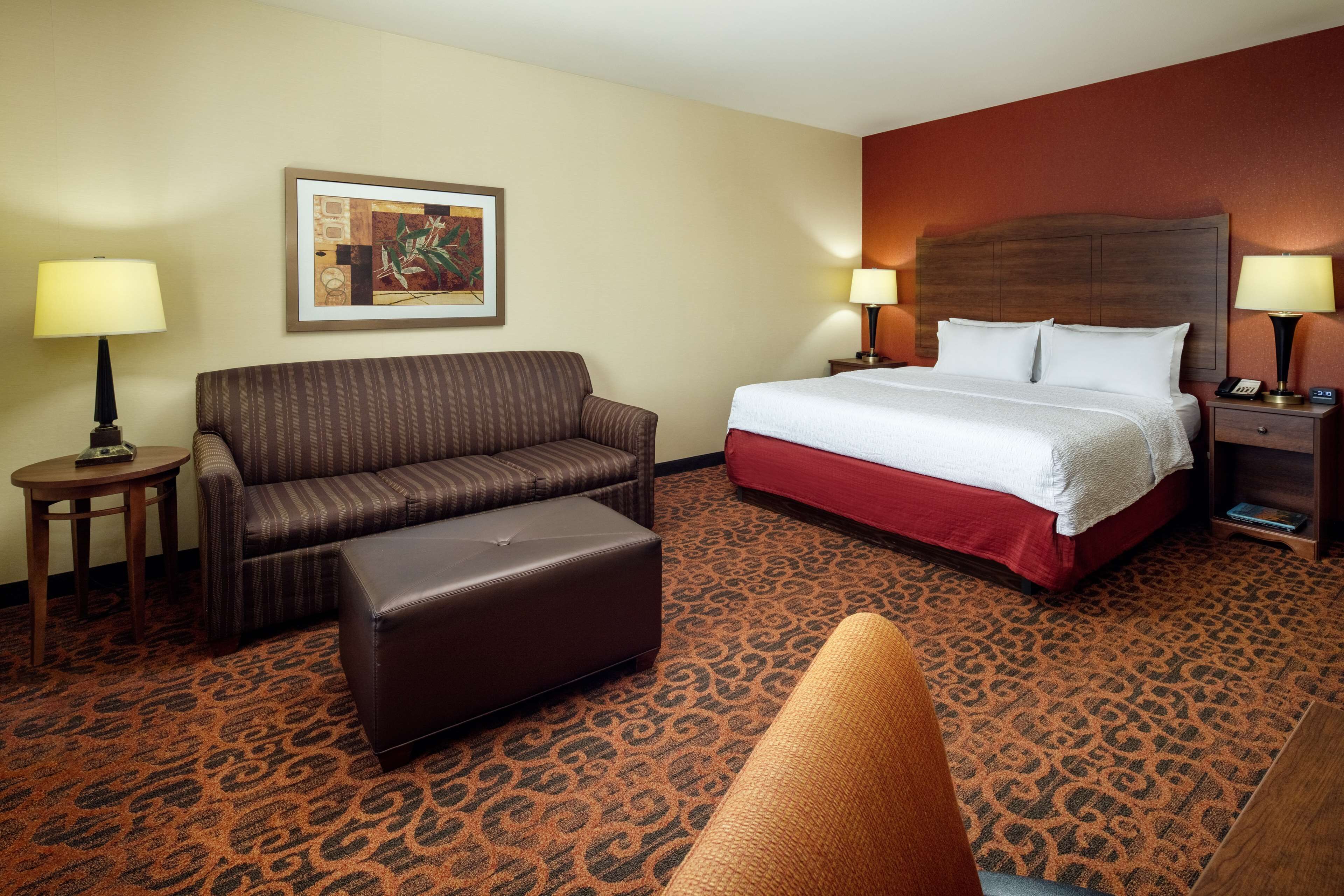 A hotel room with a bed, a sofa, a small table, and a chair.