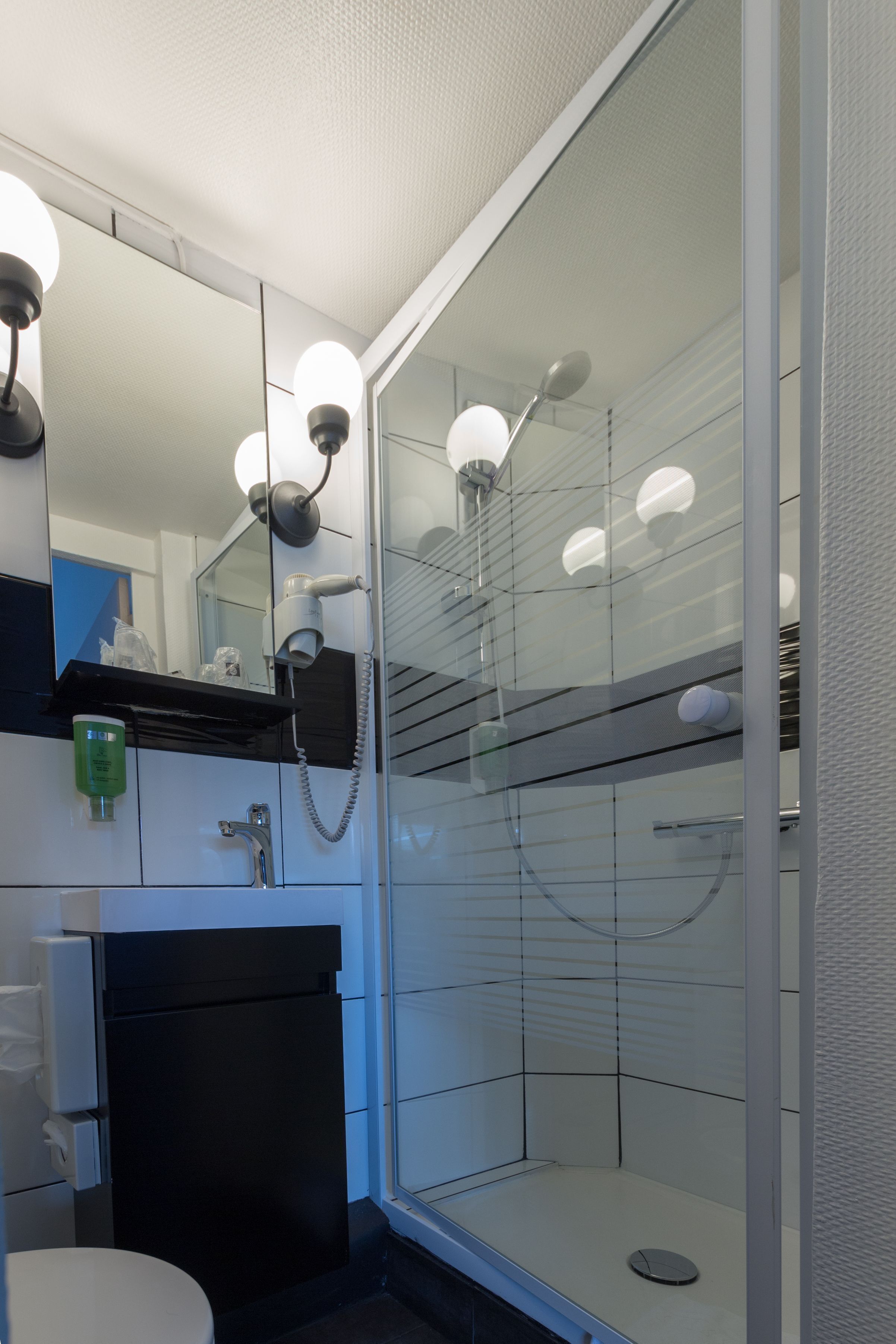 A modern bathroom with a glass shower enclosure, a sink with a mirror above, and a toilet.