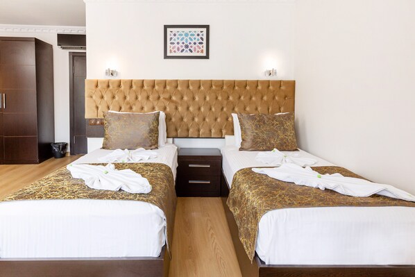Une chambre d’hôtel avec deux lits, une grande tête de lit capitonnée et une œuvre d’art encadrée accrochée au mur.