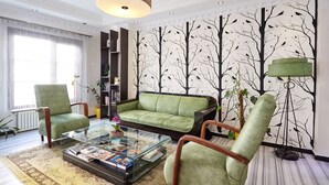 A living room with a green sofa, two armchairs, a glass coffee table, and a bookshelf. - Kumru Hotel (Istanbul)