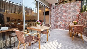 An outdoor patio with wicker furniture and a stone wall. - Kumru Hotel (Istanbul)