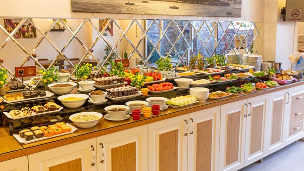 A buffet with various dishes and a cityscape view through a window. - Kumru Hotel (Istanbul)