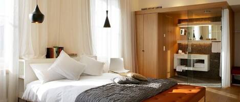 Un dormitorio moderno con cama, mesitas de noche, un banco y un vestidor con tocador.