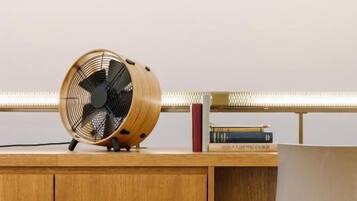A wooden desk with a fan, books, and a chair.
