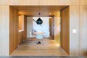 Ein modernes Interieur mit Holzvertäfelung, einem runden Tisch mit Stühlen und einer Pendelleuchte.