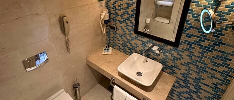 A bathroom with a white sink, a mirror, a towel rack, a hairdryer, and a phone.