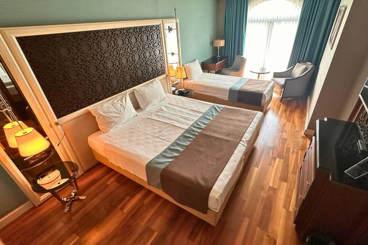 A hotel room with a large bed, a smaller bed, a desk, and a chair.