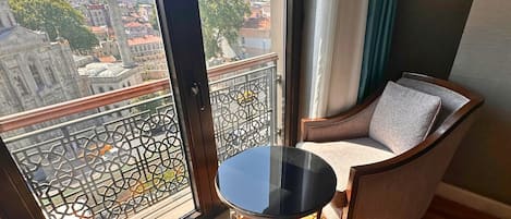 Un balcon donnant sur un paysage urbain, une table ronde et un fauteuil rembourré.