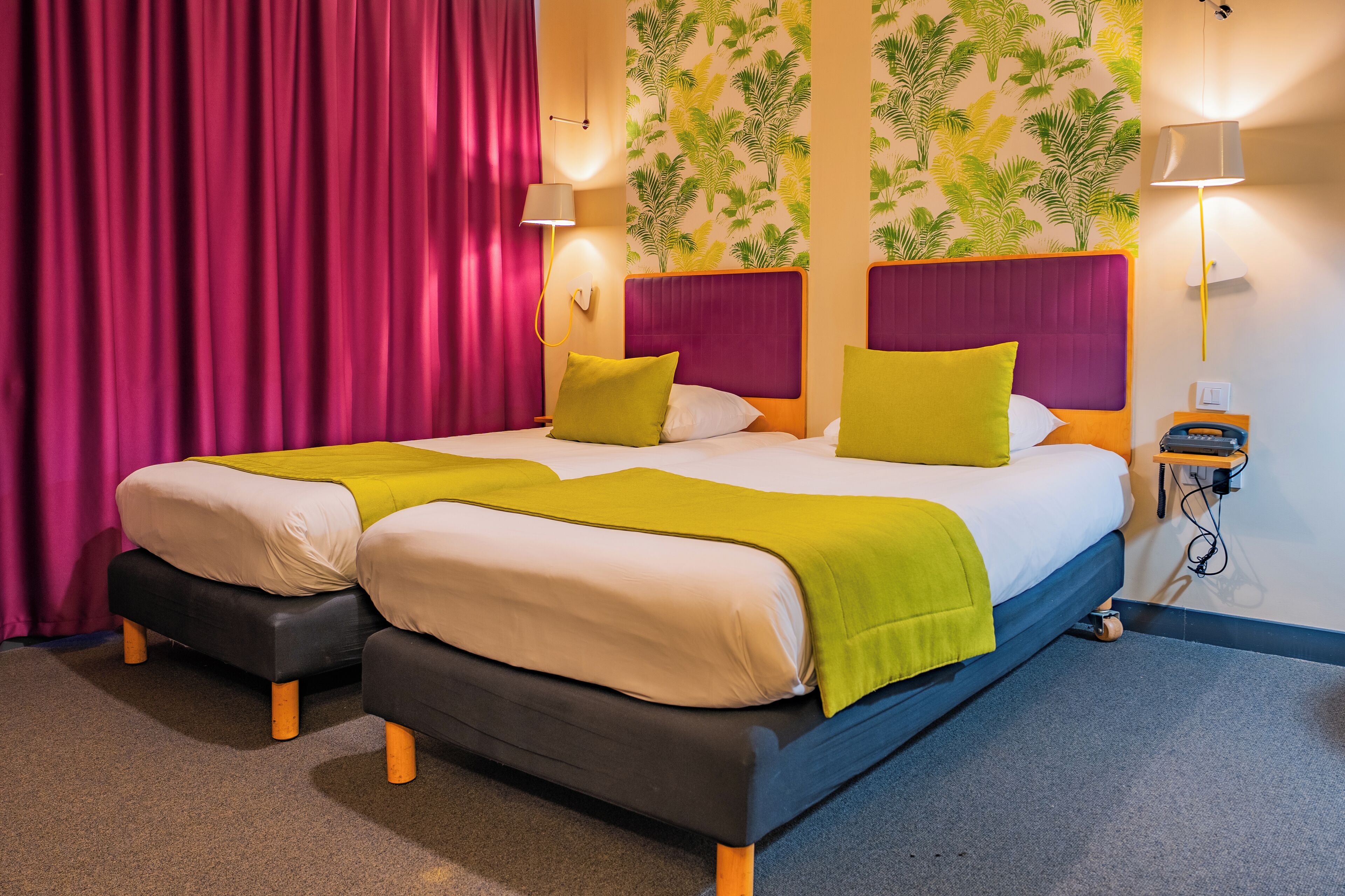 A double bed with a yellow and white bedspread, two pillows, and a nightstand with a lamp.