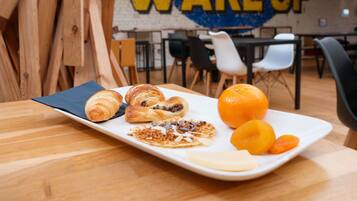 A breakfast setting with croissants, a fruit plate, and a wall with 'WAKE UP' graffiti.