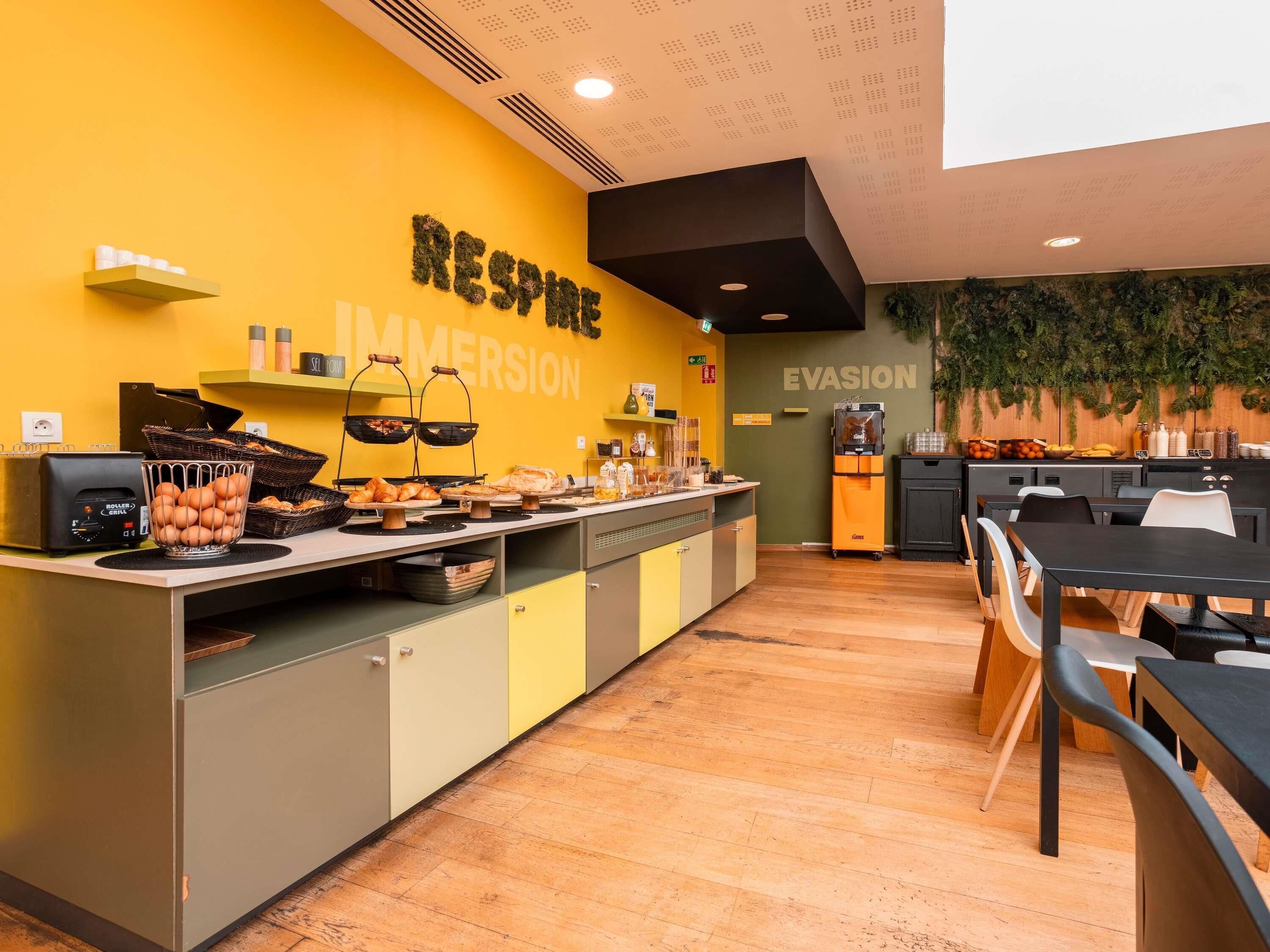 A modern kitchen with a yellow wall, a buffet counter, and a seating area with a table and chairs.