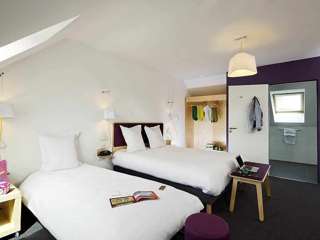 Une chambre d’hôtel avec deux lits, une petite table, une chaise, un bureau et une armoire.