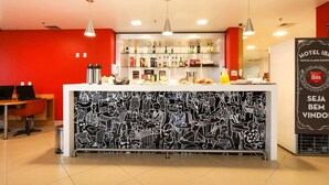 Zona de recepción de un hotel con una barra, un mostrador y una pared con un mural en blanco y negro.