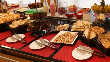 A buffet with various food items including breads, pastries, and desserts.
