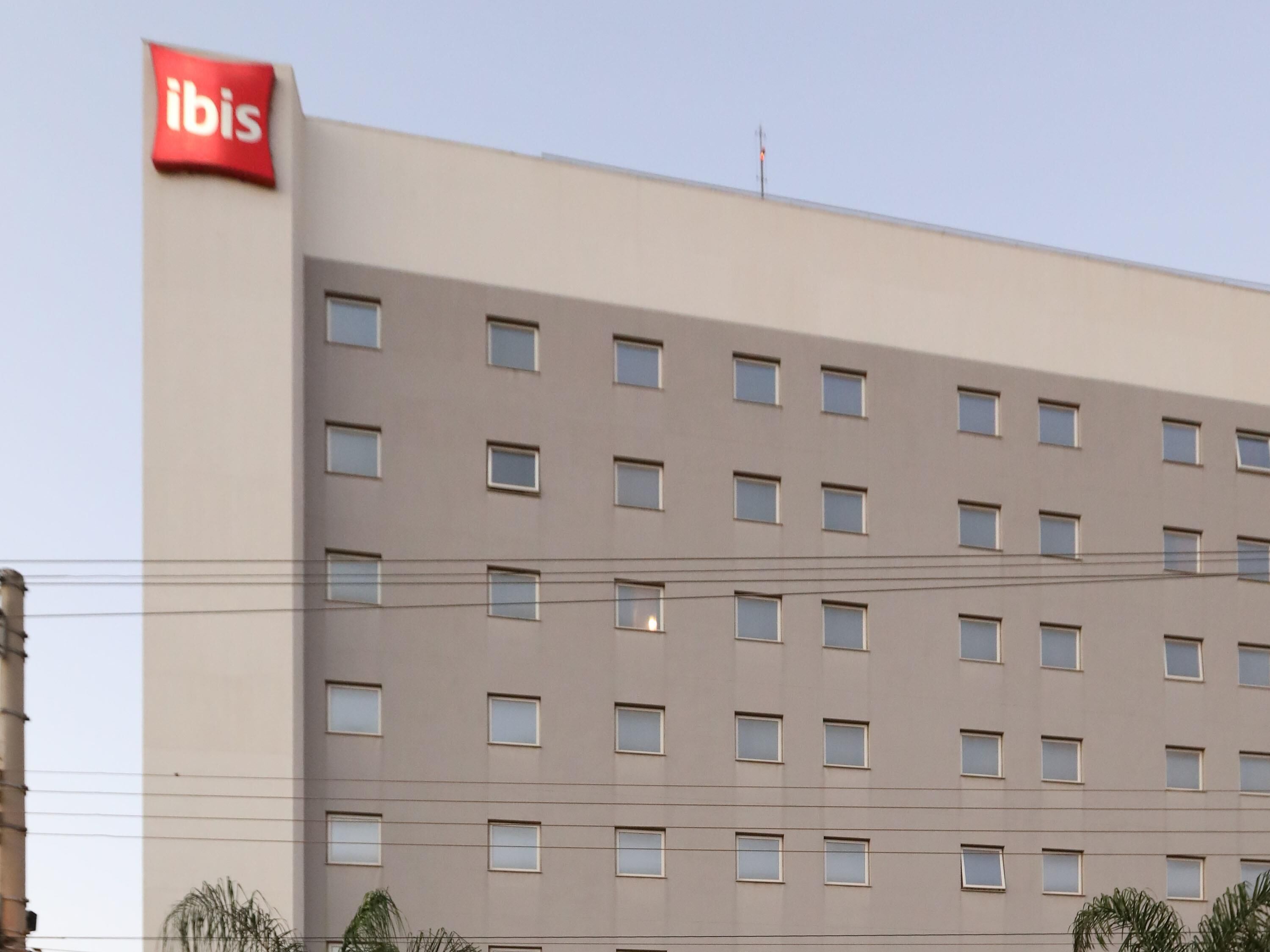 Un edificio de hotel de varios pisos con un llamativo letrero rojo de 'ibis' en el lado izquierdo.
