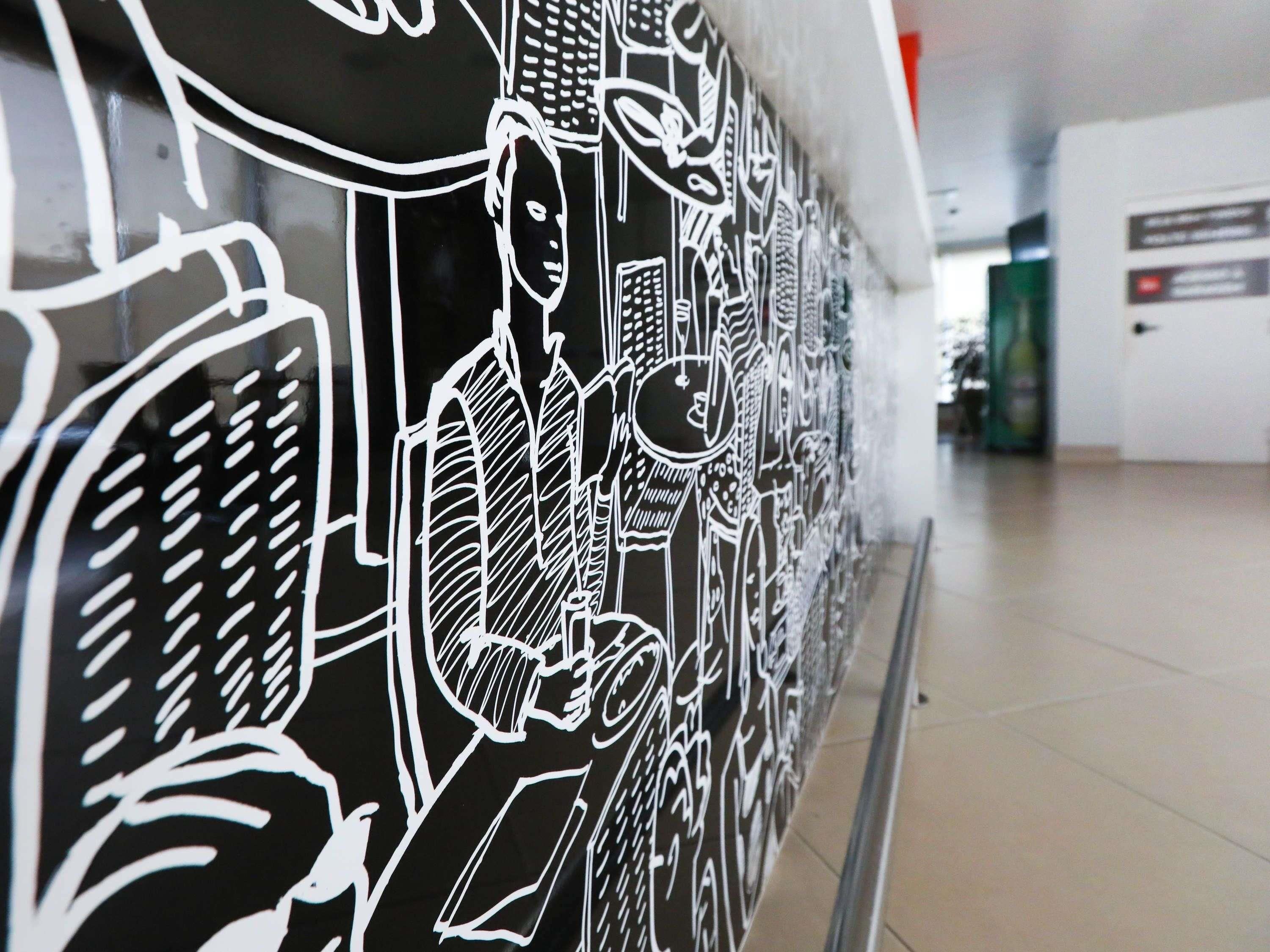A wall with a black and white mural of various architectural and urban elements.