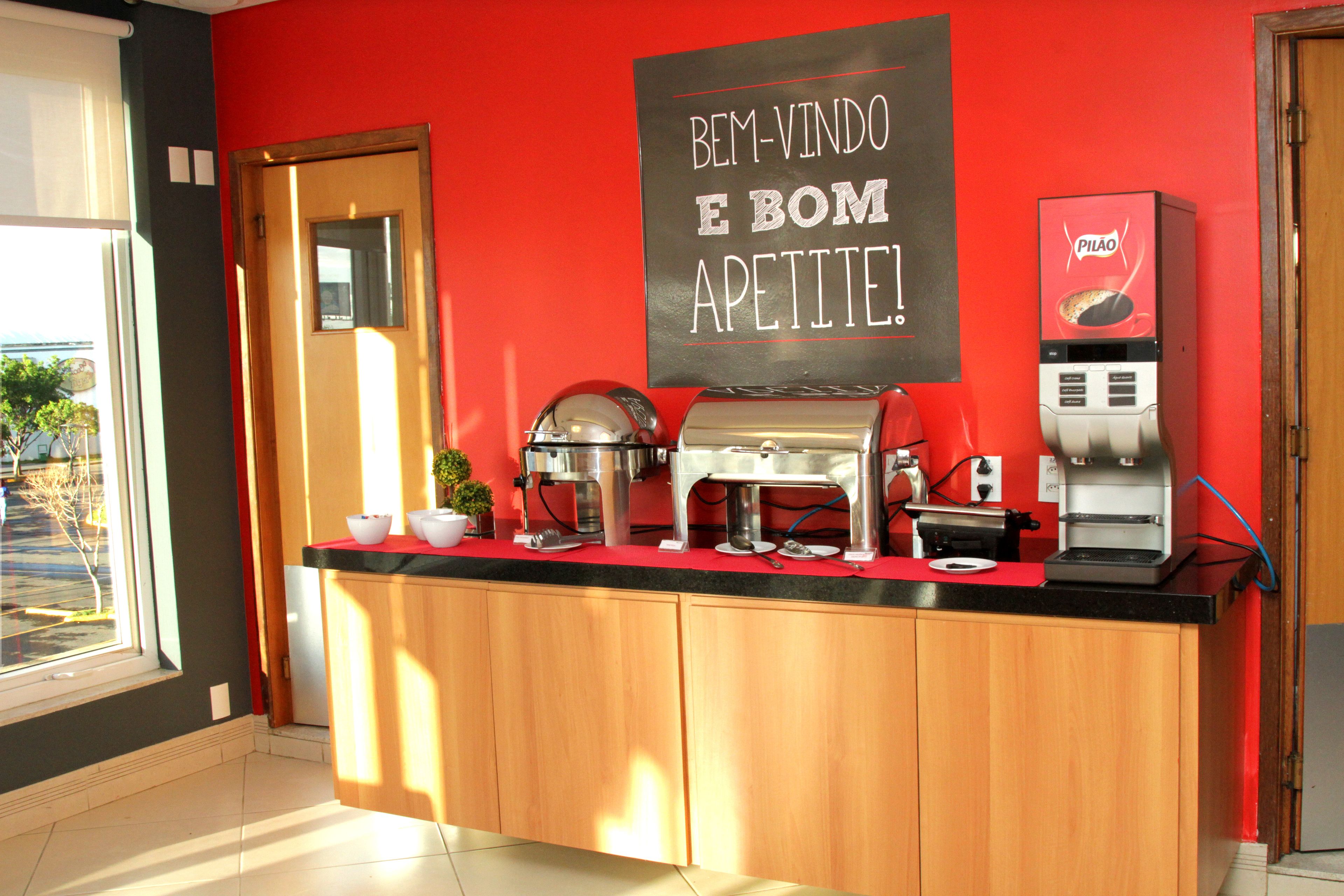 Un coin cuisine équipé d’une machine à café, d’un tableau noir sur lequel est écrit un message, et d’une fenêtre donnant sur l’extérieur.