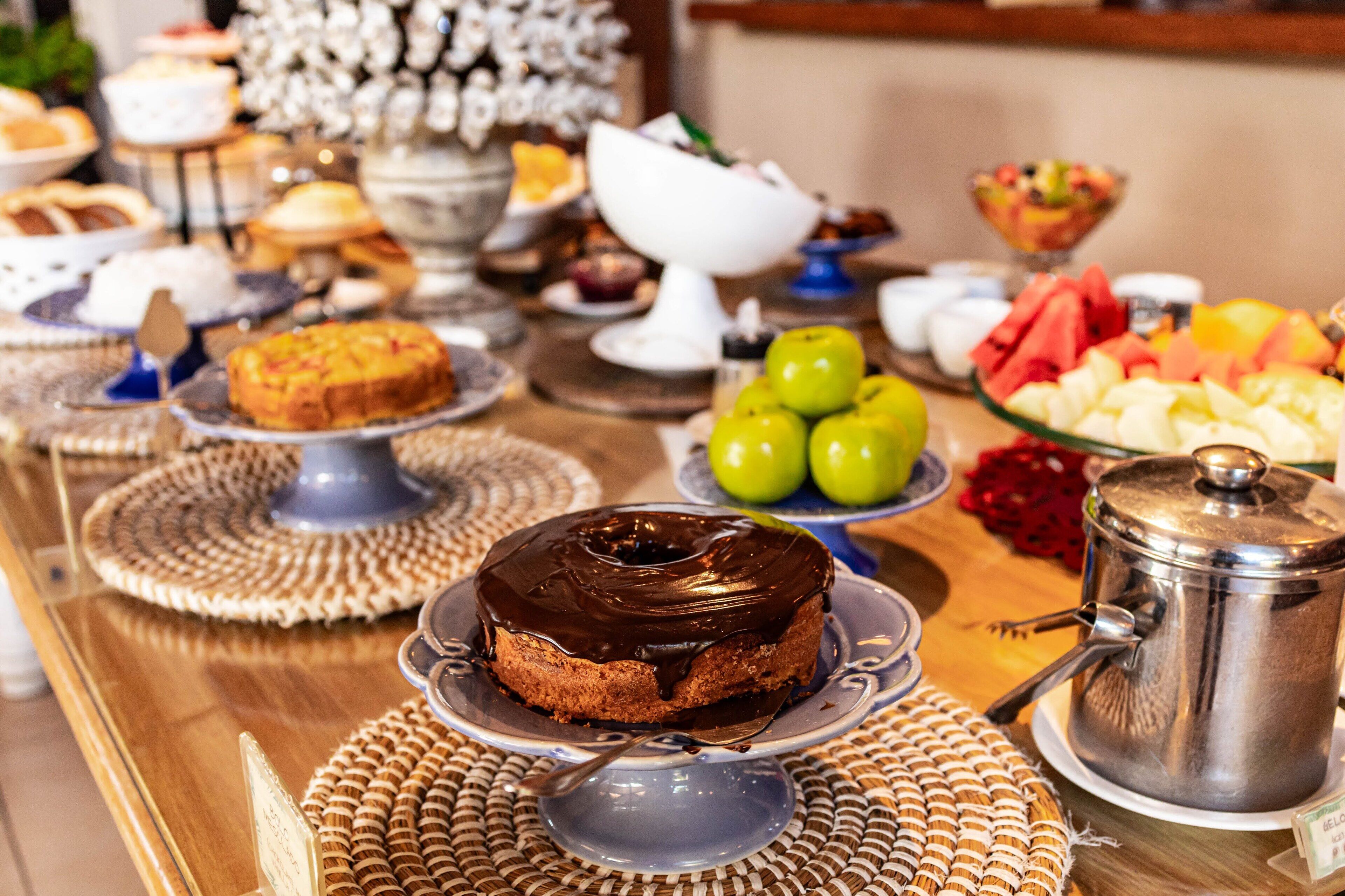 Une table de buffet proposant divers plats, notamment un gâteau au chocolat, des fruits et une cafetière.