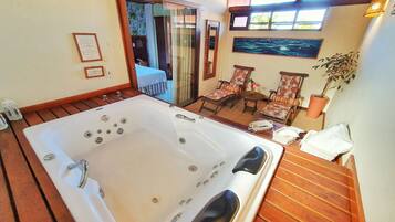 Une salle de bain avec une grande baignoire, un plancher en bois et une petite table avec des chaises.