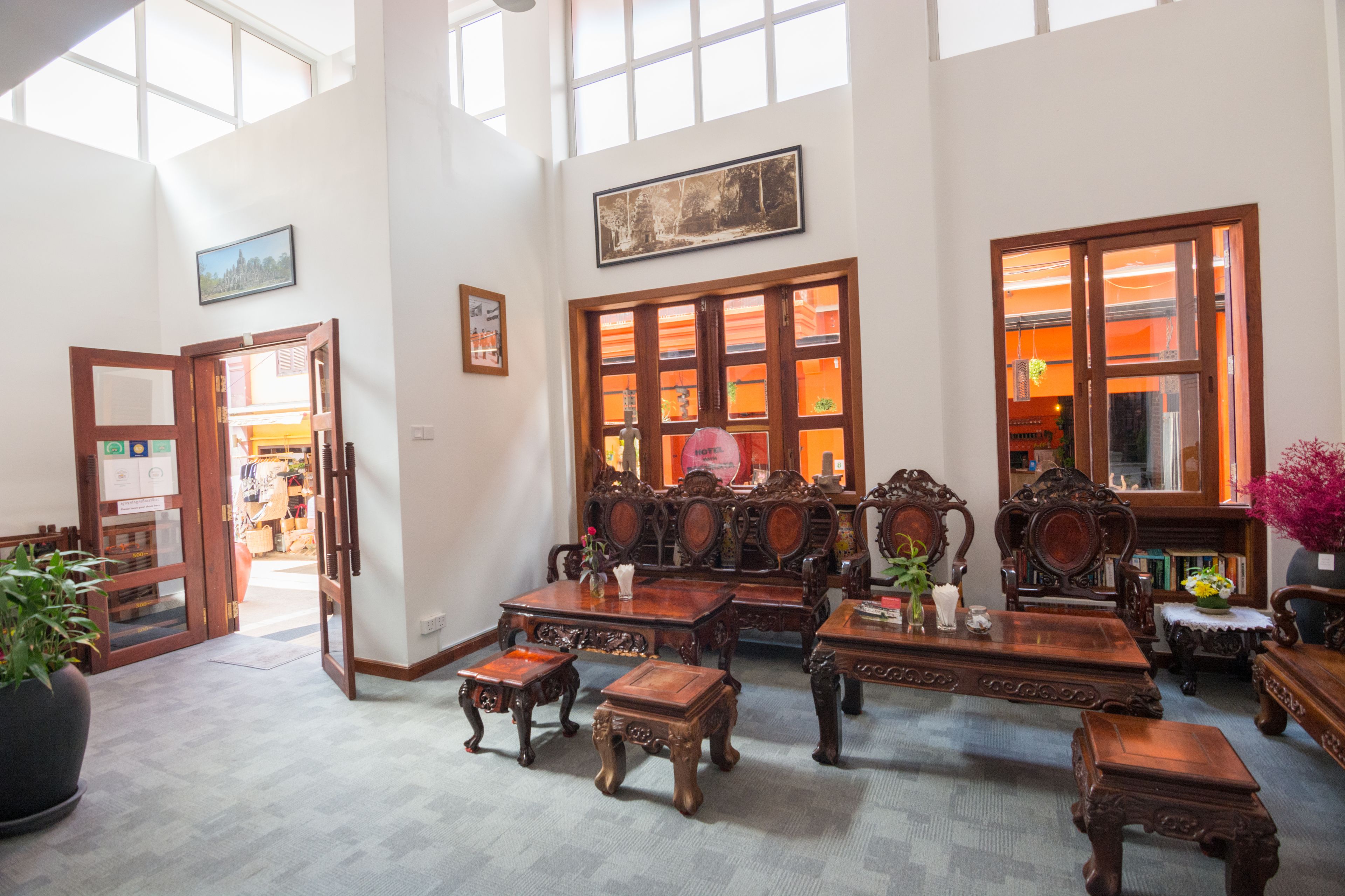 A spacious room with high ceilings, large windows, and a variety of wooden furniture including tables and chairs.